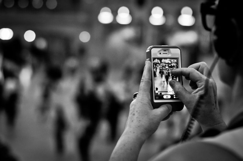 Cropped image of woman photographing mobile phone