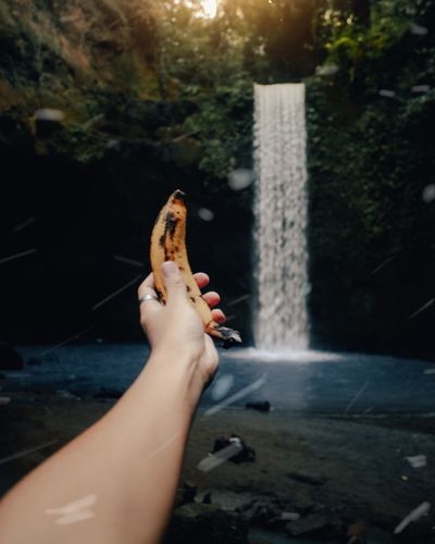  man/woman holding a banana in a waterfall with blue colors