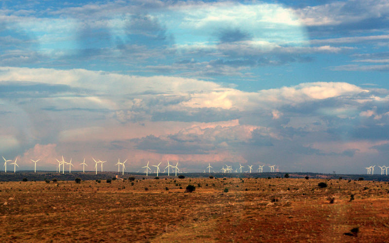 Distance shot of wind turbines on landscape against sky