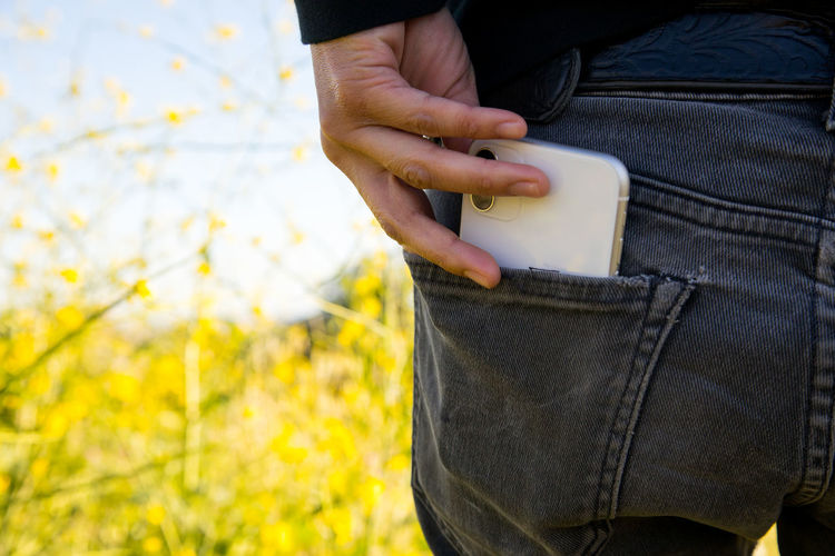 Woman pulling cell phone out of pants pocket in nature