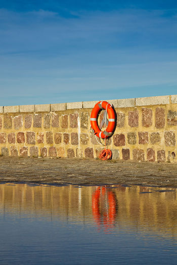 Life belt on wall at shore against blue sky