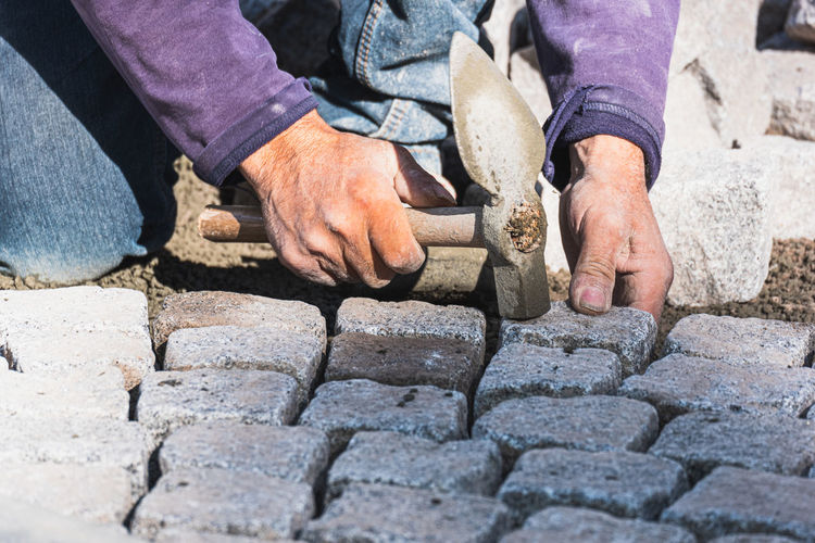 Close-up of a man working with cobblestones at a construction site