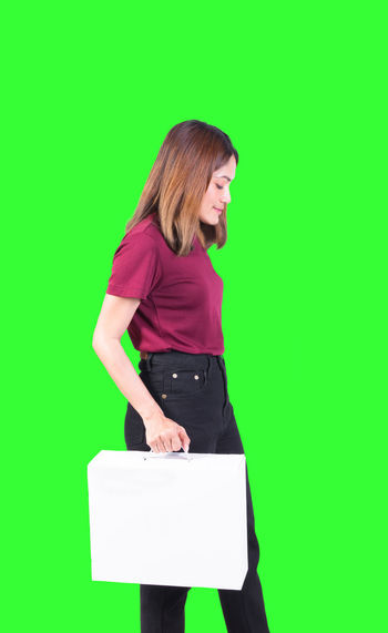 Full length of a woman standing against green background