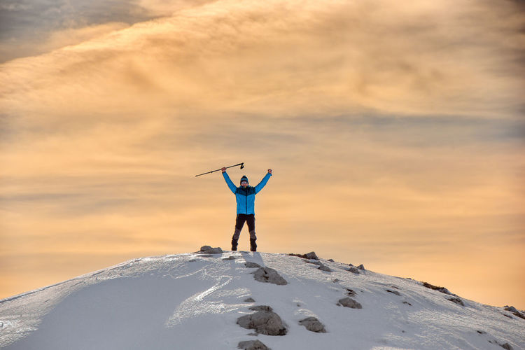 Full length of man standing on snow covered mountain against sky