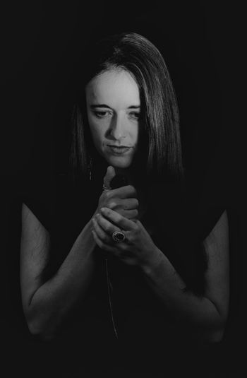 Thoughtful woman holding knife against black background