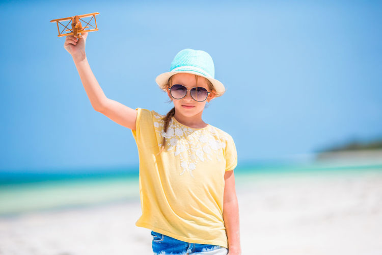 Portrait of girl holding toy airplane at beach