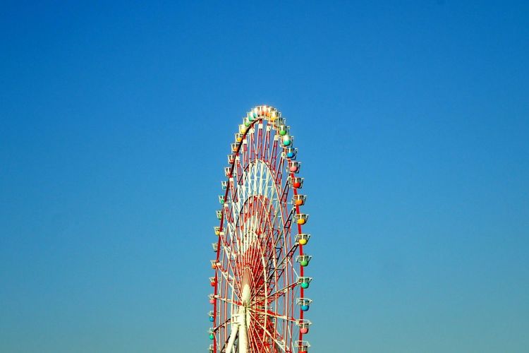 Low angle view of ferris wheel against clear blue sky