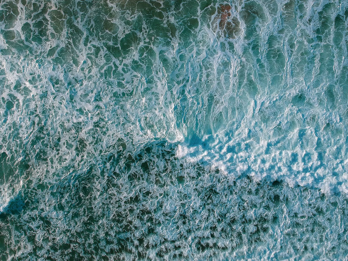 Drone view of beautiful turquiose sea waves breaking on sandy coastline. aerial shot 