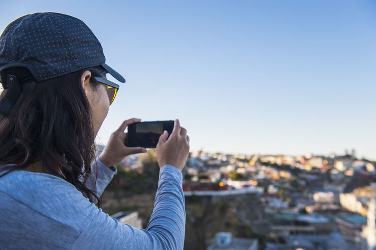 Woman taking photograph with smartphone, valparaiso in chile