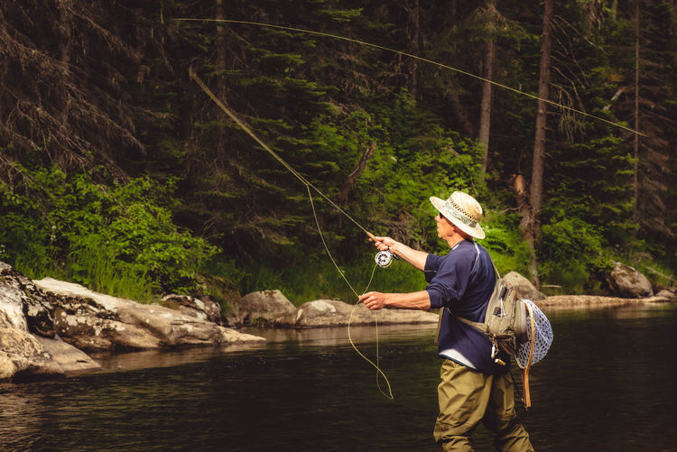 Rear view of man wearing hat fishing in river