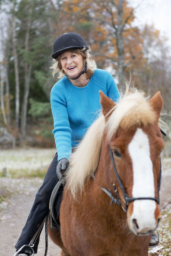 Senior woman riding on icelandic horse