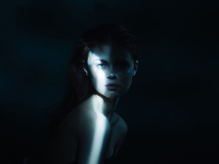 Portrait of serious young woman over black background