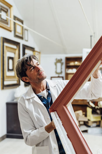 Craftsman examining wooden frame in workshop