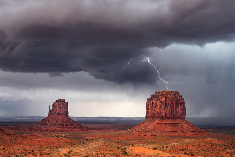 Scenic view of lightning over rocks against cloudy sky