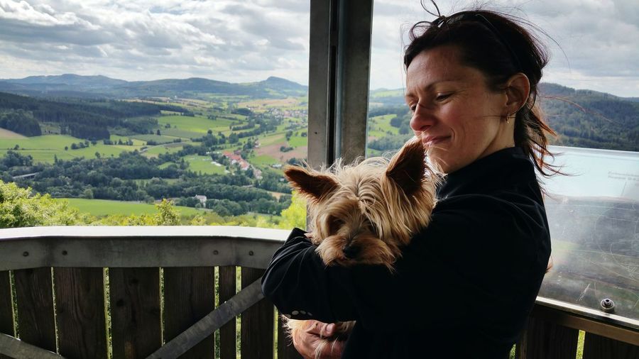 Close-up of mature woman holding dog while standing at observation point