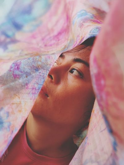 Close-up of young woman looking away seen through blanket