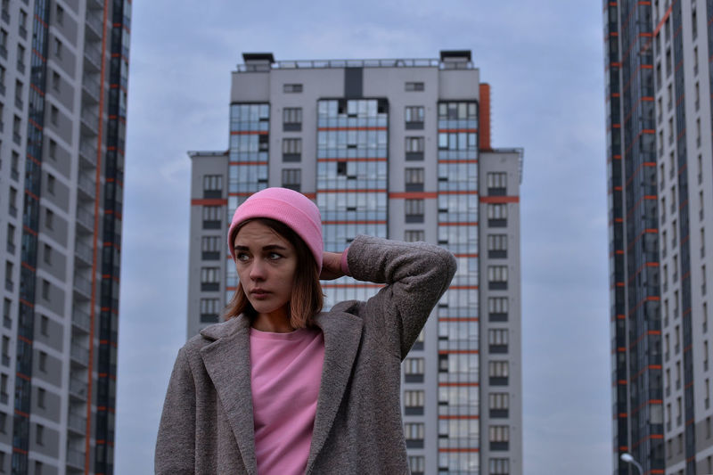 Young woman standing against buildings in city
