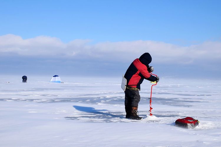 Man drilling hole in ice