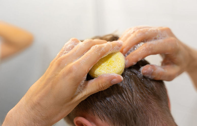 A man applies a solid shampoo bar to the hair. sustainable hair care. man in the bathroom
