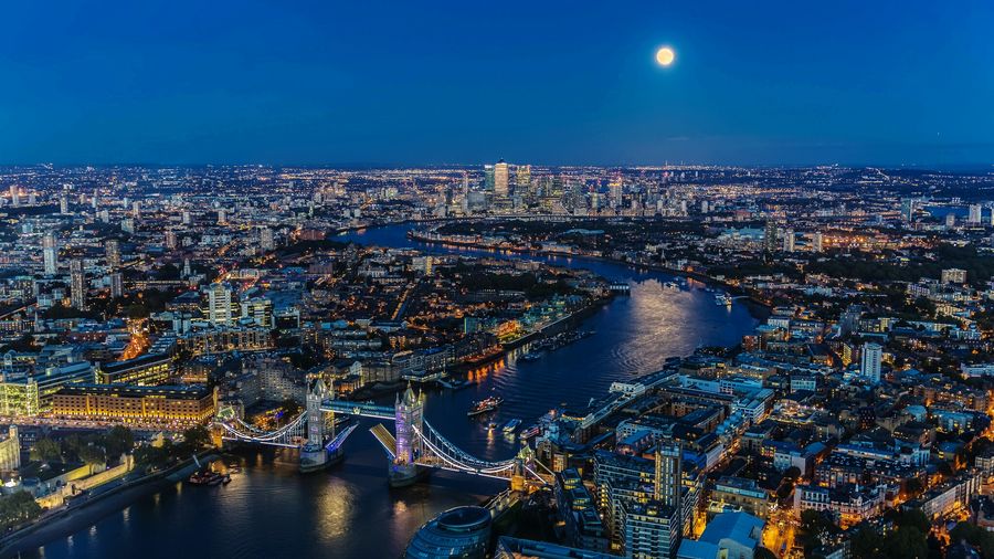 High angle view of tower bridge over thames river amidst cityscape at night