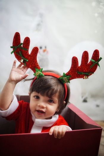 Portrait of cute girl in santa claus costume while sitting in box