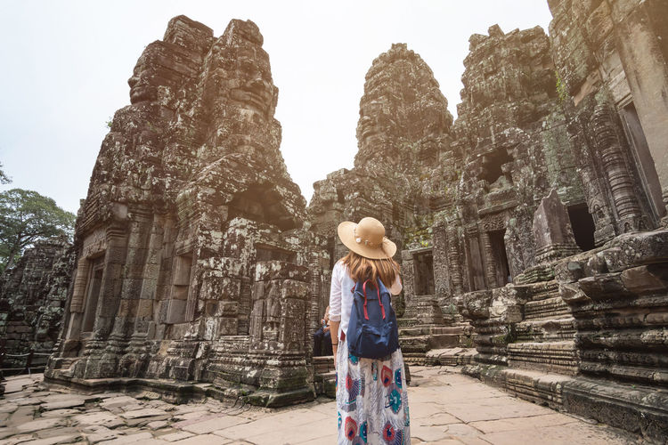Rear view of woman wearing hat while standing by old temple