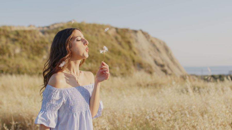 Young woman drinking water against sky