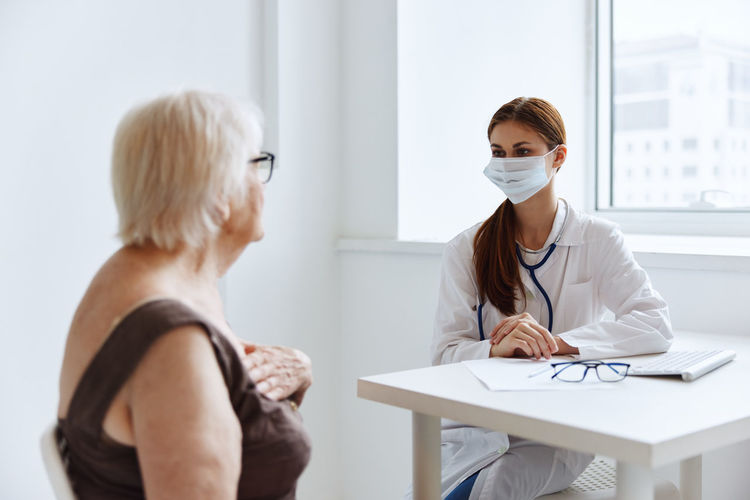 Doctor wearing mask taking to patient