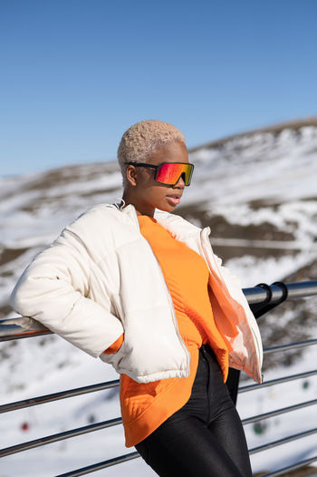Una mujer afroamericana con gafas de pie en una montaña nevada durante el invierno