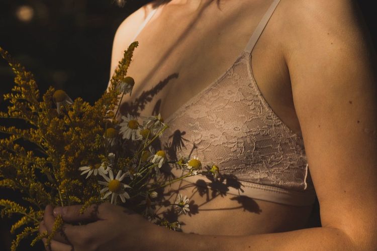 Midsection of woman with flowers at home