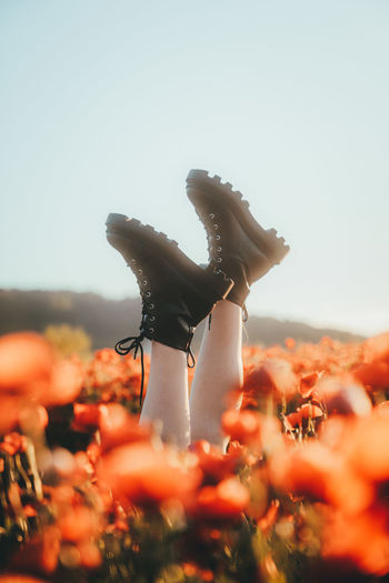 Midsection of woman with boots raised against clear sky