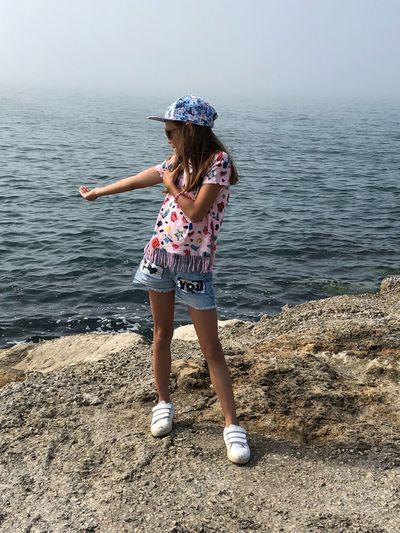 Full length of girl gesturing while standing at beach