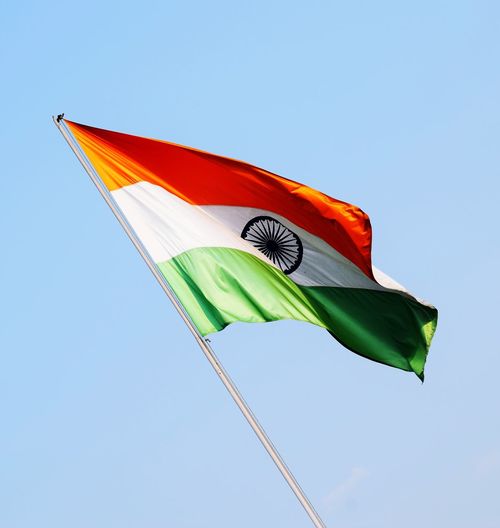 Low angle view of indian flag against clear blue sky
