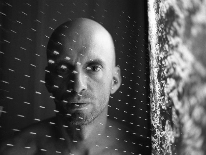 CLOSE-UP PORTRAIT OF A MAN WITH REFLECTION OF BLURRED BACKGROUND