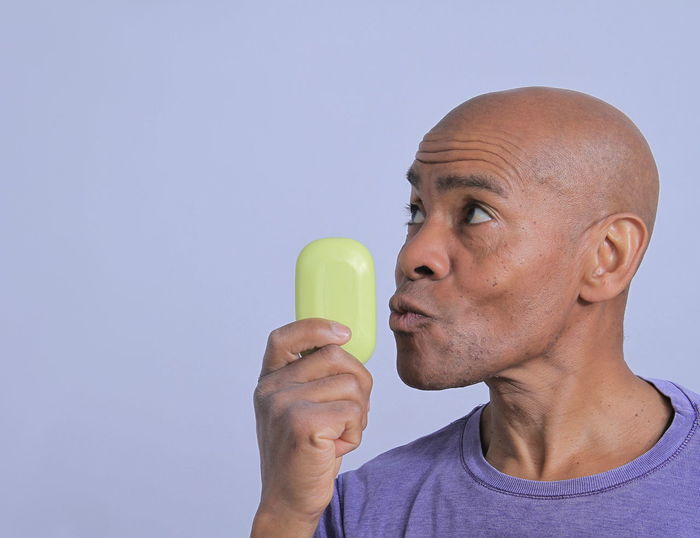 Portrait of man holding ice cream against white background