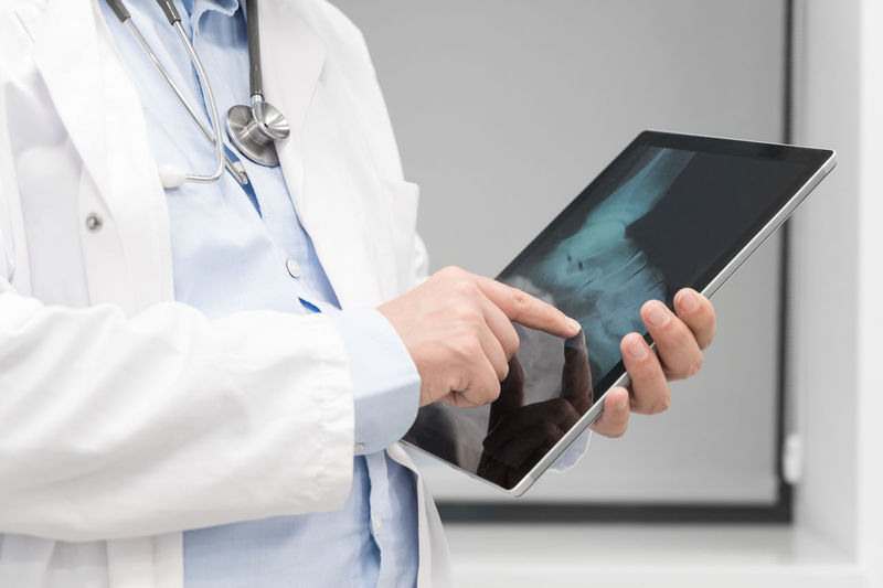 Midsection of doctor using digital tablet