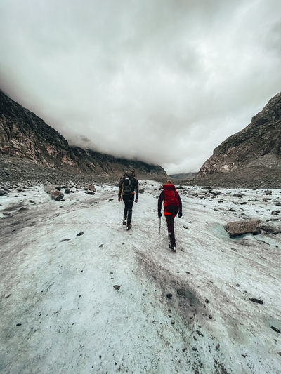 Two climbers hiking on glacier under cloudy sky