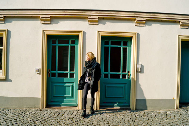Full length of young woman standing against building on sunny day