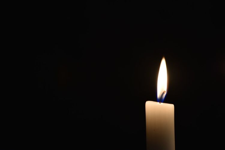 Close-up of burning candle in darkroom