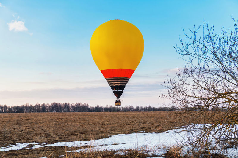Hot air balloon flying over field against sky