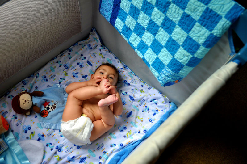 High angle view of cute baby boy lying in crib at home