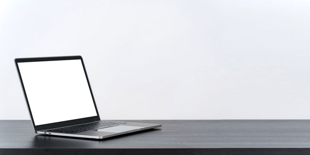 Empty laptop on table against white background