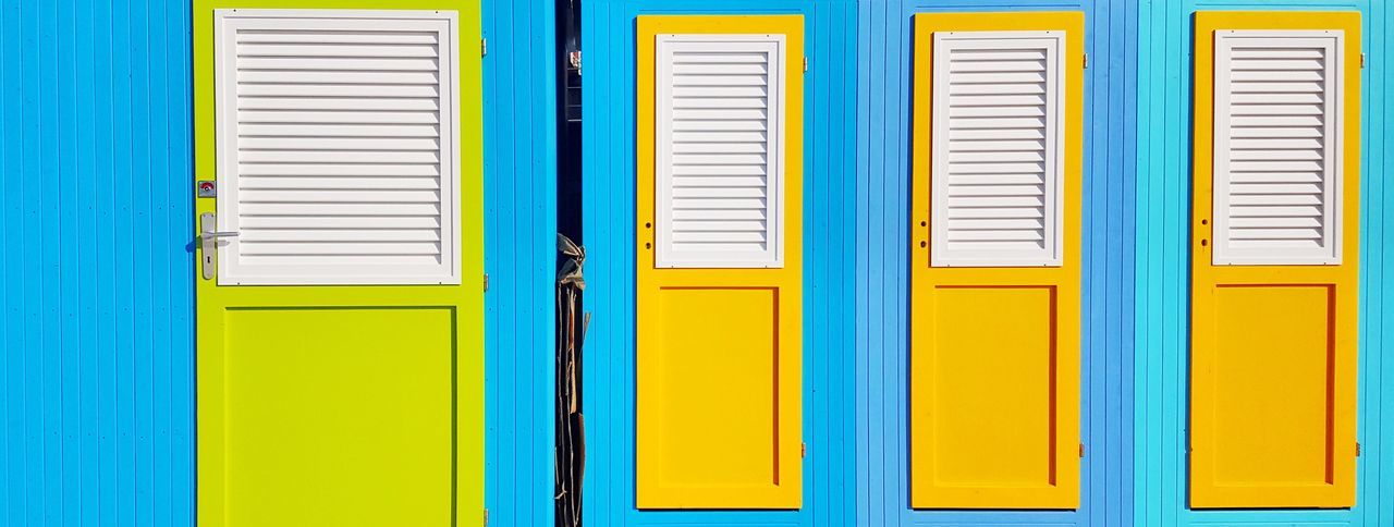 Closed yellow doors of blue beach huts