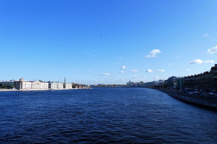 View of river and buildings against blue sky