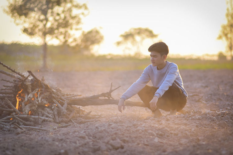 A young man in winter was sitting by the fire to alleviate the cold, lifestyle thailand.