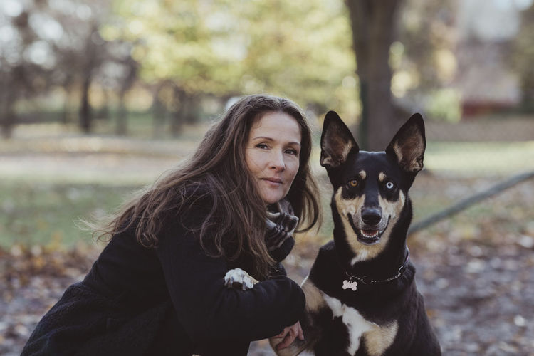 Side view portrait of smiling woman with dog at park