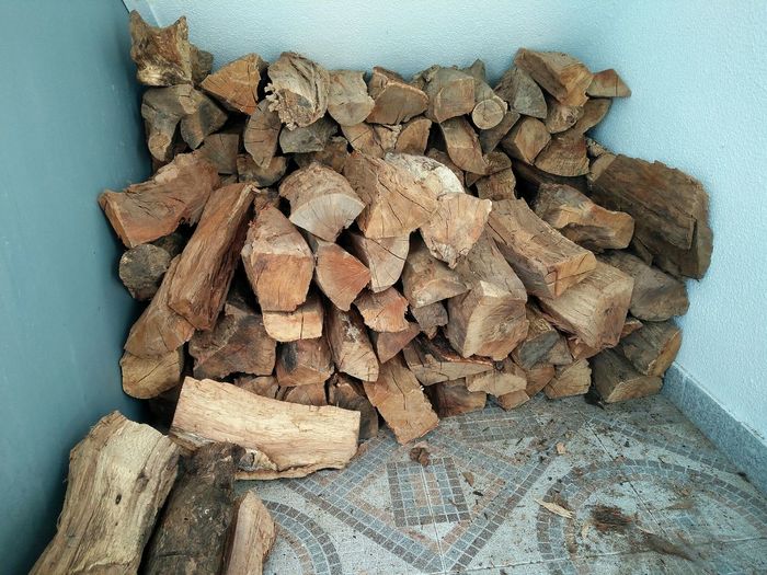 Close-up of stack of logs against wall