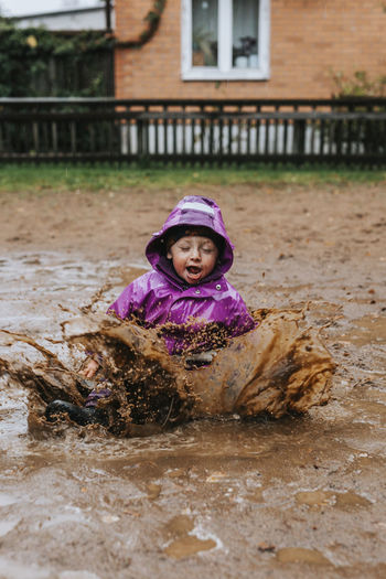 Toddler girl splashing in puddle
