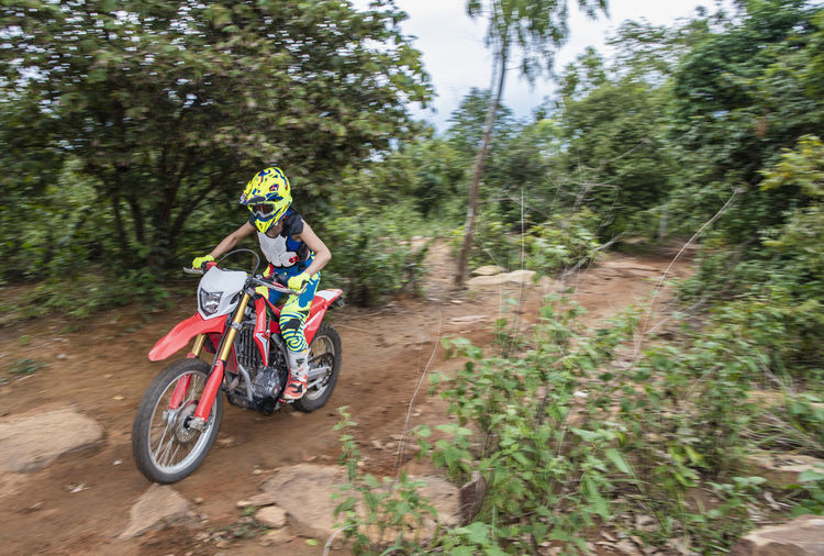 Woman riding her dirt-bike on forest track in pak chong / thailand