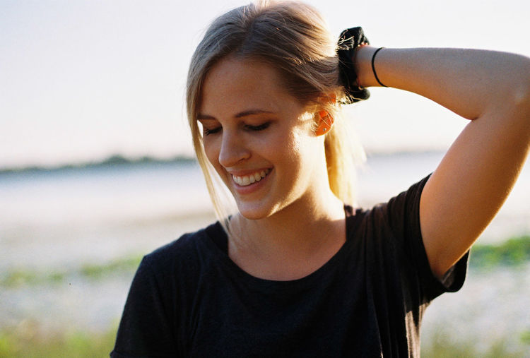 Portrait of smiling young woman against sky